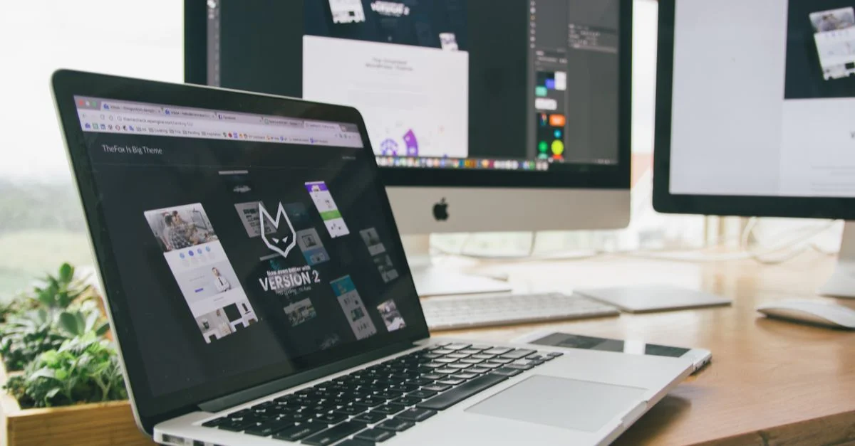 Un espace de travail élégant avec un ordinateur portable et des moniteurs affichant un logiciel de design.